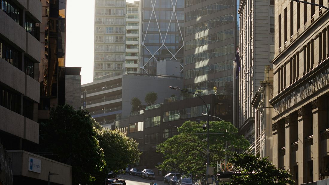 A person crossing an Auckland city street in early morning sunlight
