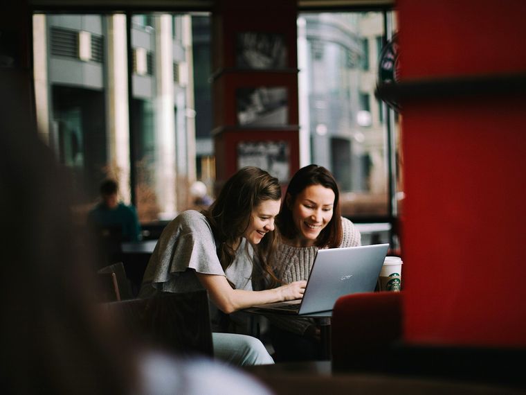 Two co-founders looking at a laptop screen together in a cafe