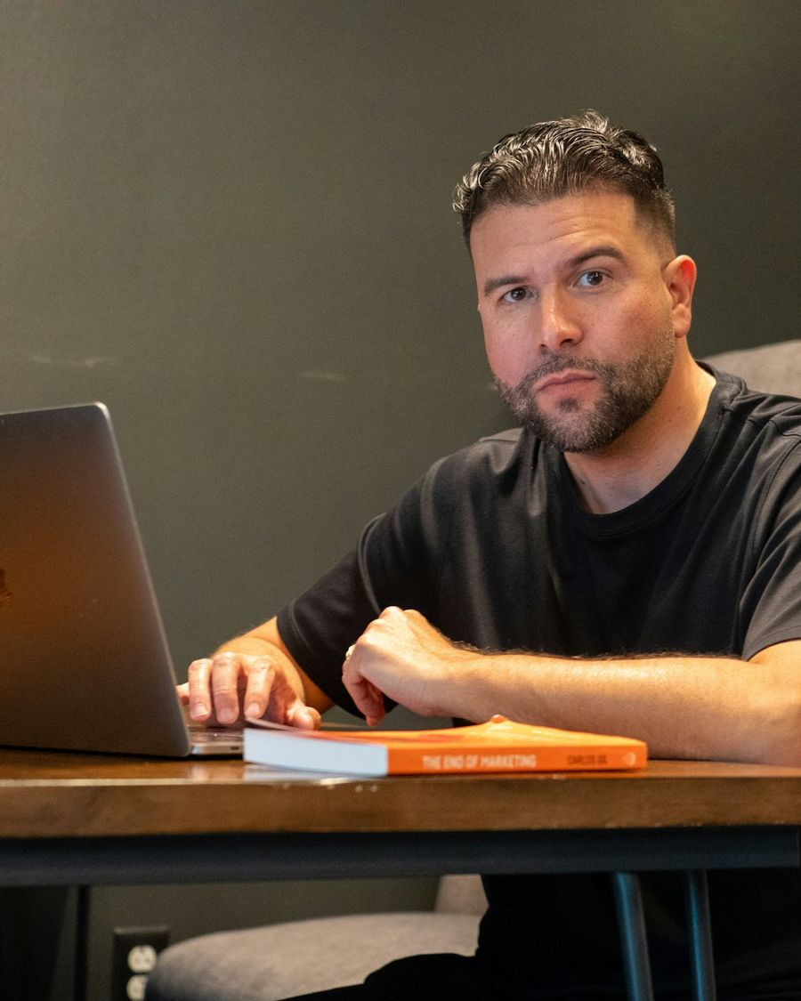 A young founder in a black t-shirt planning on a laptop at a wooden table