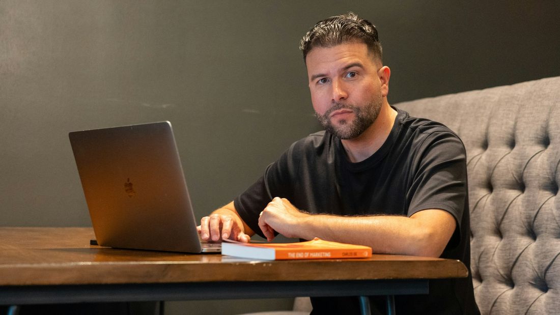 A young founder in a black t-shirt planning on a laptop at a wooden table
