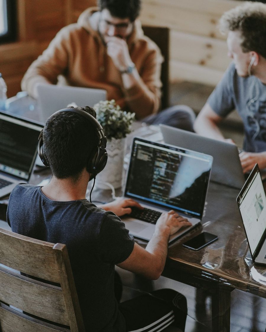 A small tech team gathered around a laptop working through a product plan